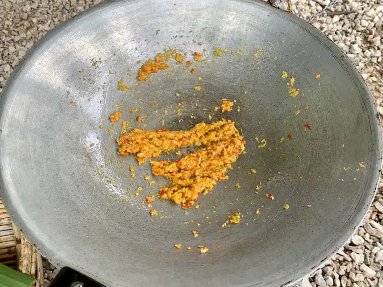 Sauteed lemongrass, chili, and garlic mixture cooking in oil in a wok.