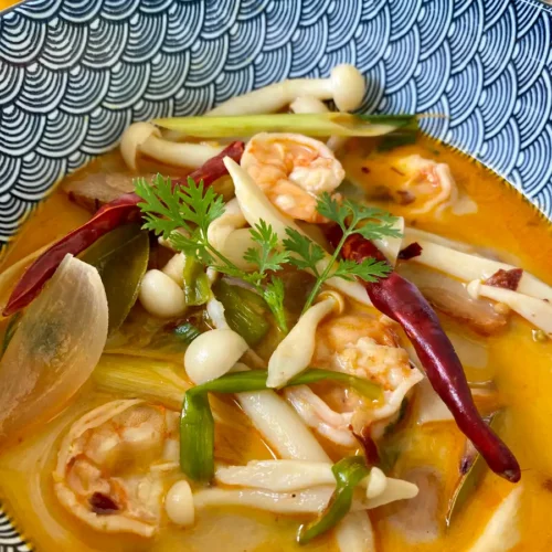 Tom yum kung, spicy Thai shrimp soup, served in a patterned bowl.