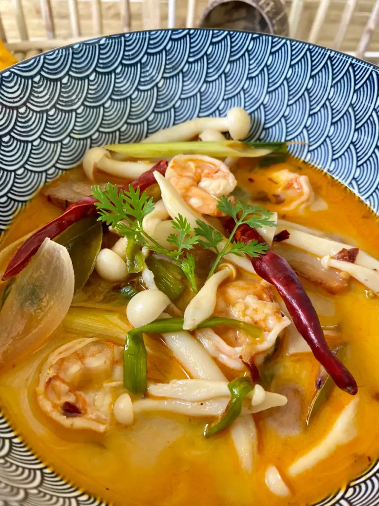 Tom yum kung, spicy Thai shrimp soup, served in a patterned bowl.