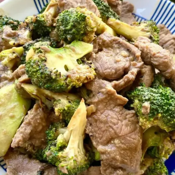 Close-up of authentic Thai beef and broccoli stir-fry served in a white dish.