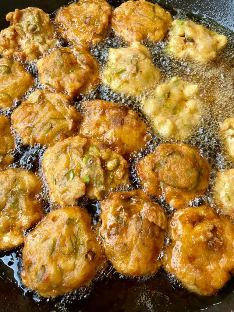 Thai fish cakes, Tod Mun Pla, frying to a golden brown in a pan of hot oil.