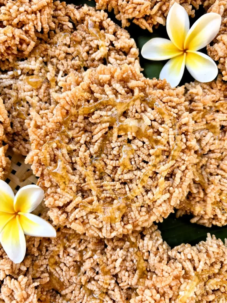 Thai crispy rice cakes with a honey glaze resting on a banana leaf.