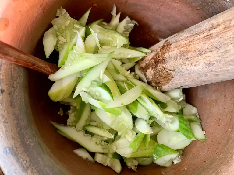 Fresh sliced cucumber added to the mortar with dressing and vegetables.