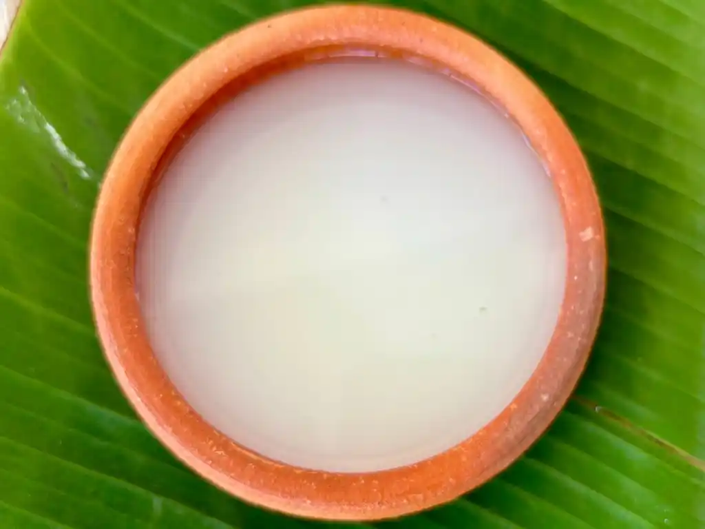 Terracotta bowl of cornstarch and water mixture resting on a fresh green banana leaf, a thickening agent for sauces.