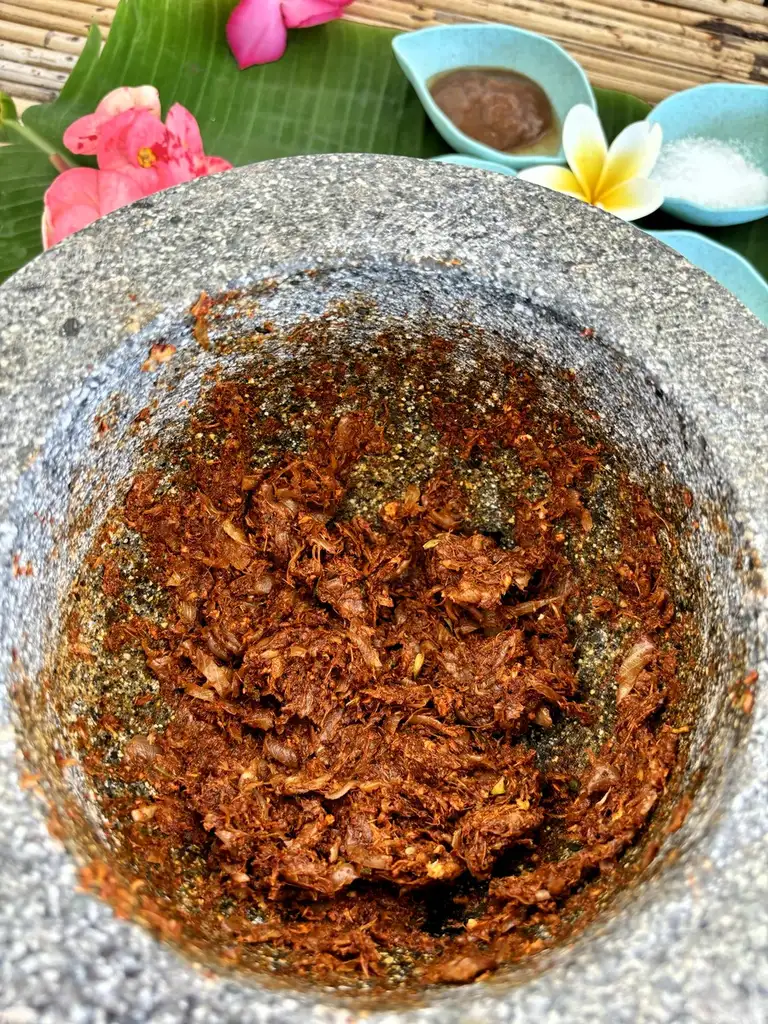 Lao jeow bong dipping sauce in a granite mortar, a blend of chili and herbs.