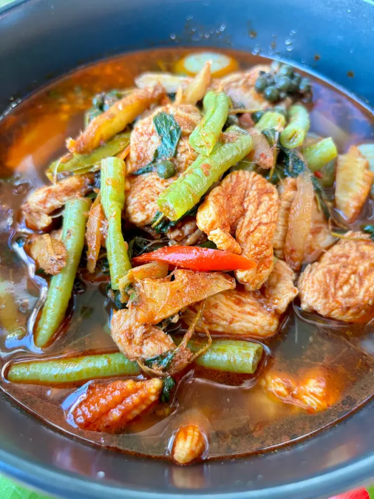 Close-up of kaeng pa, Thai jungle curry, highlighting the clear, spicy broth, vegetables, and chicken.