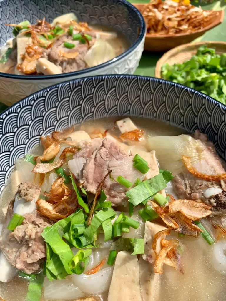 Lao pork noodle soup with tender pork slices, chewy rice noodles, and a garnishing of fried onions and shallots.