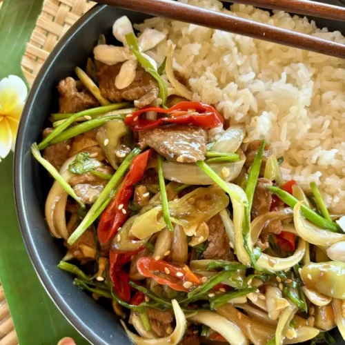 Nua pad prik, a spicy Thai beef stir-fry served over steamed jasmine rice in a black bowl.