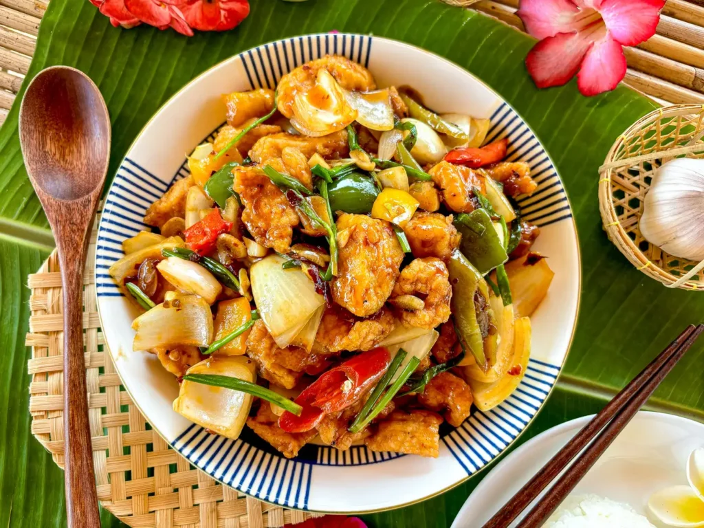 Thai pad prik pao chicken stir-fry with colorful bell peppers, onions, and rice in the background.