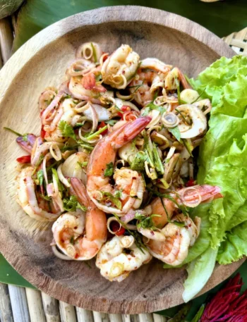 Pla goong, spicy Thai shrimp salad, served in a wooden dish with lettuce.