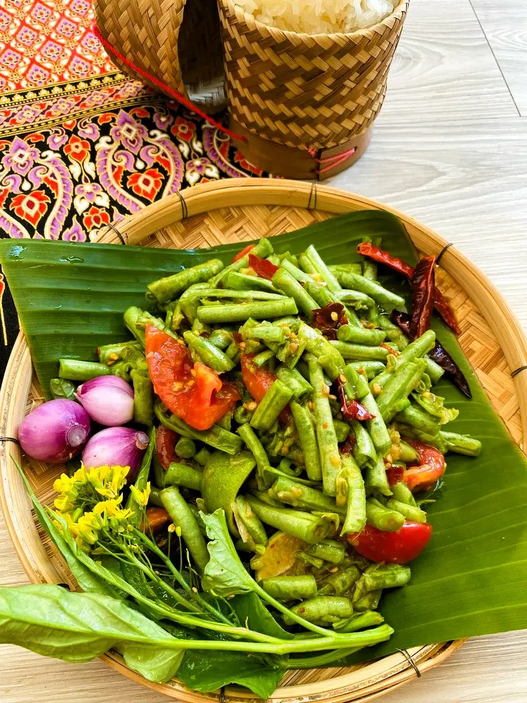 Colorful and crunchy som tum tua with vegetables and spicy dressing, with a portion of sticky rice.