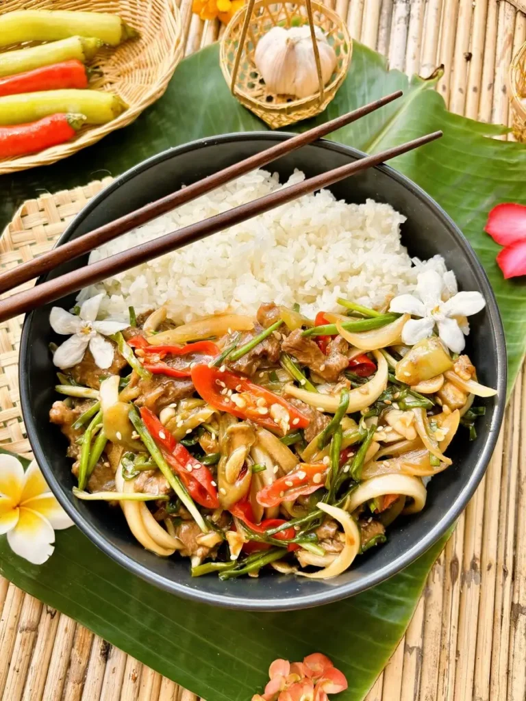 Thai chili beef stir-fry in a black dish on a banana leaf, served with rice for an easy dinner.