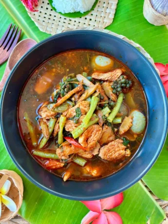Authentic Thai jungle curry with chicken and mixed vegetables, served in a spicy broth garnished with holy basil and chilies.