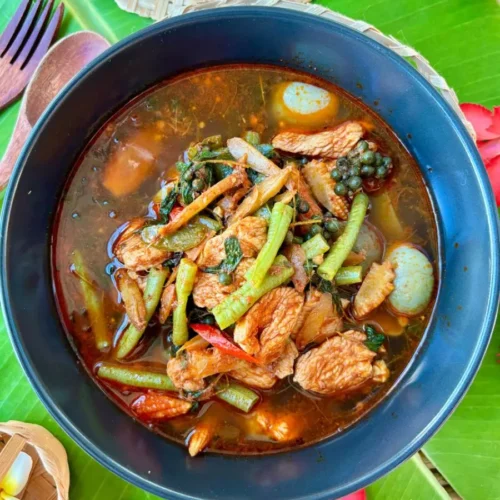 Authentic Thai jungle curry with chicken and mixed vegetables, served in a spicy broth garnished with holy basil and chilies.