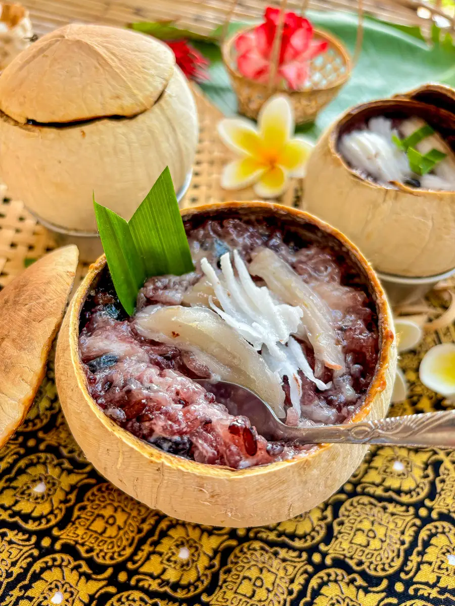 Traditional Thai khao lam, sticky rice with coconut and black beans, served in a coconut shell for a Thai dessert.