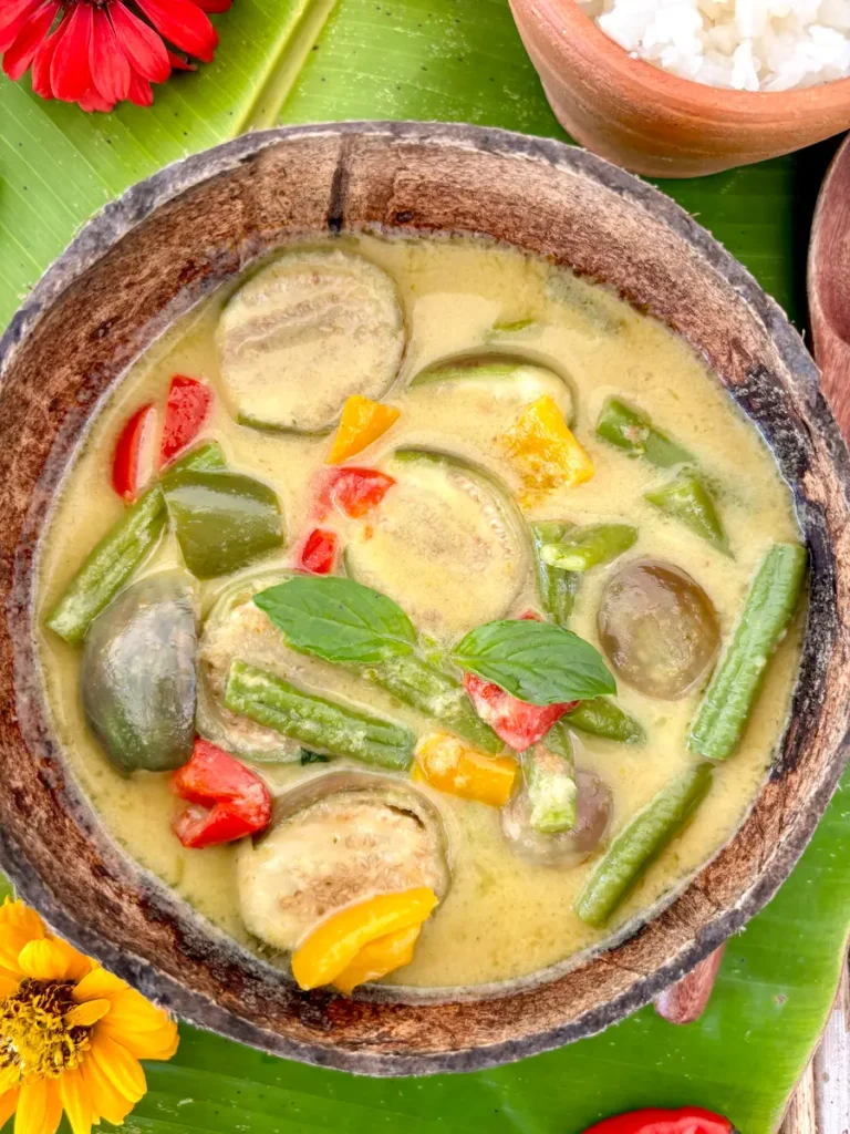 Vegetarian Thai green curry with vegetables served in a coconut shell.