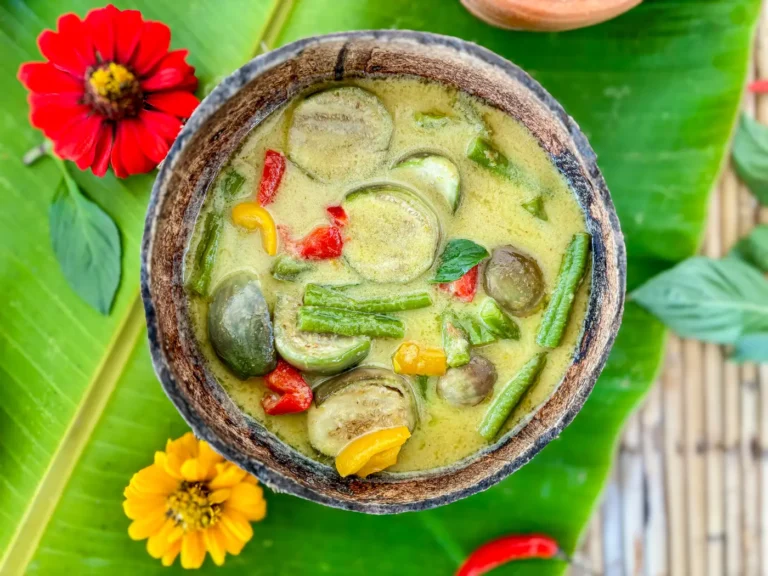 Vegetarian Thai green curry with vegetables and coconut milk served in a coconut shell.