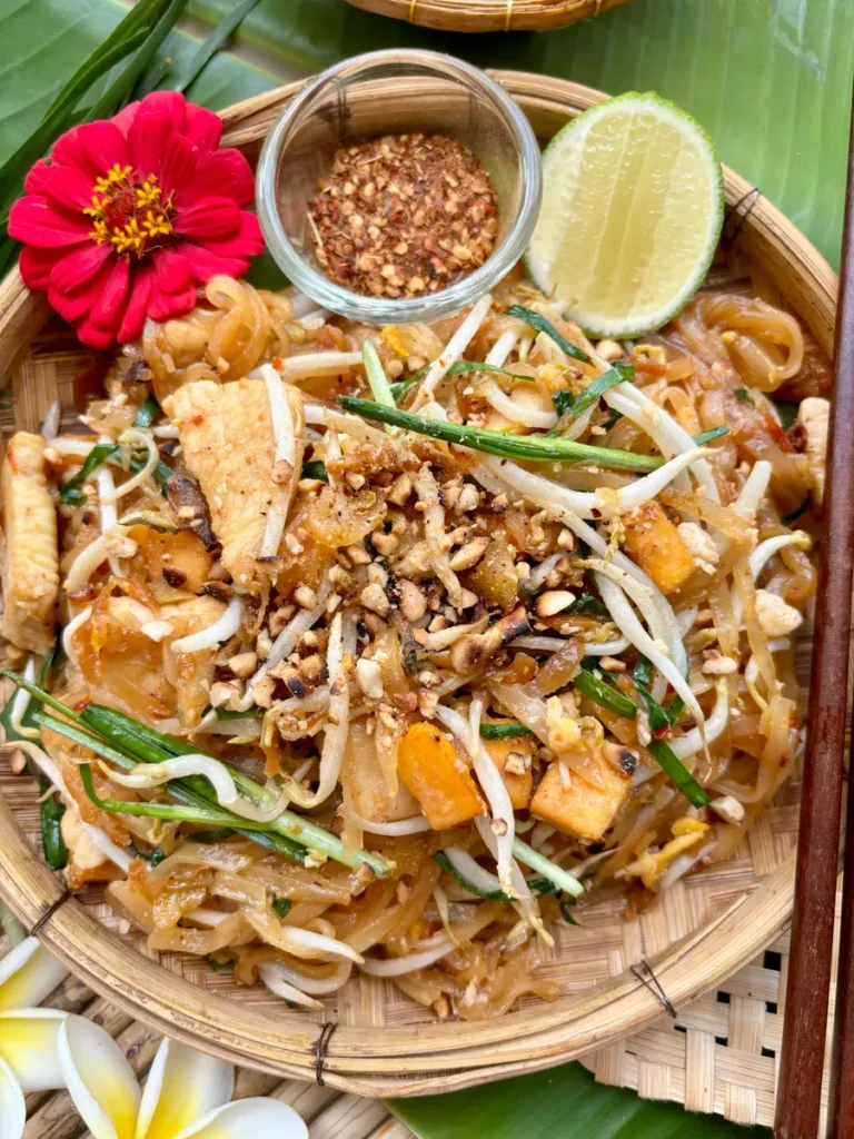 Close-up of authentic pad Thai garnished with fresh herbs, bean sprouts, and peanuts.