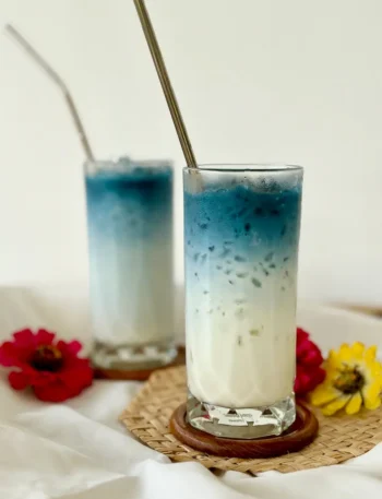 Two tall glasses of butterfly pea milk tea.