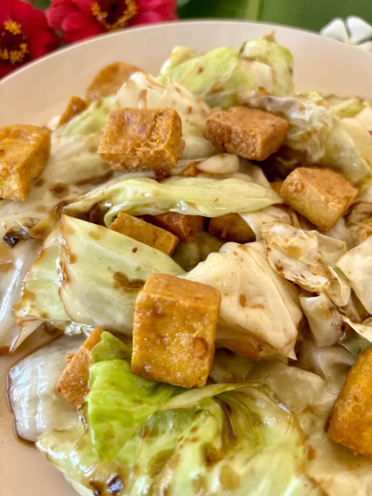 Close-up of crispy fried cabbage with tofu, coated with stir-fry sauce.