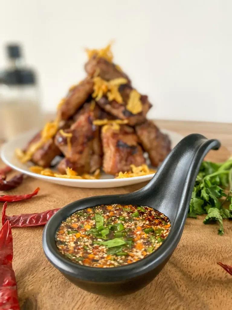 Spicy dipping sauce with a tower of Thai BBQ ribs.