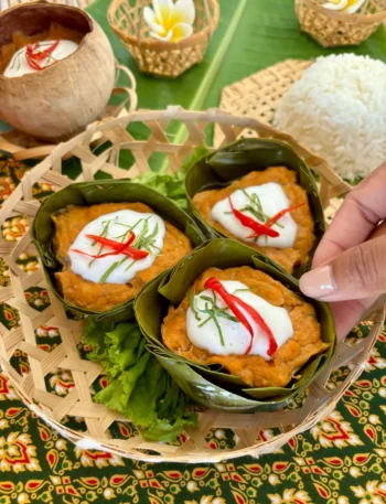 Traditional Thai hor mok pla served in banana leaf bowls, topped with red chili, kaffir lime and coconut cream, ready to be enjoyed with steamed jasmine rice.