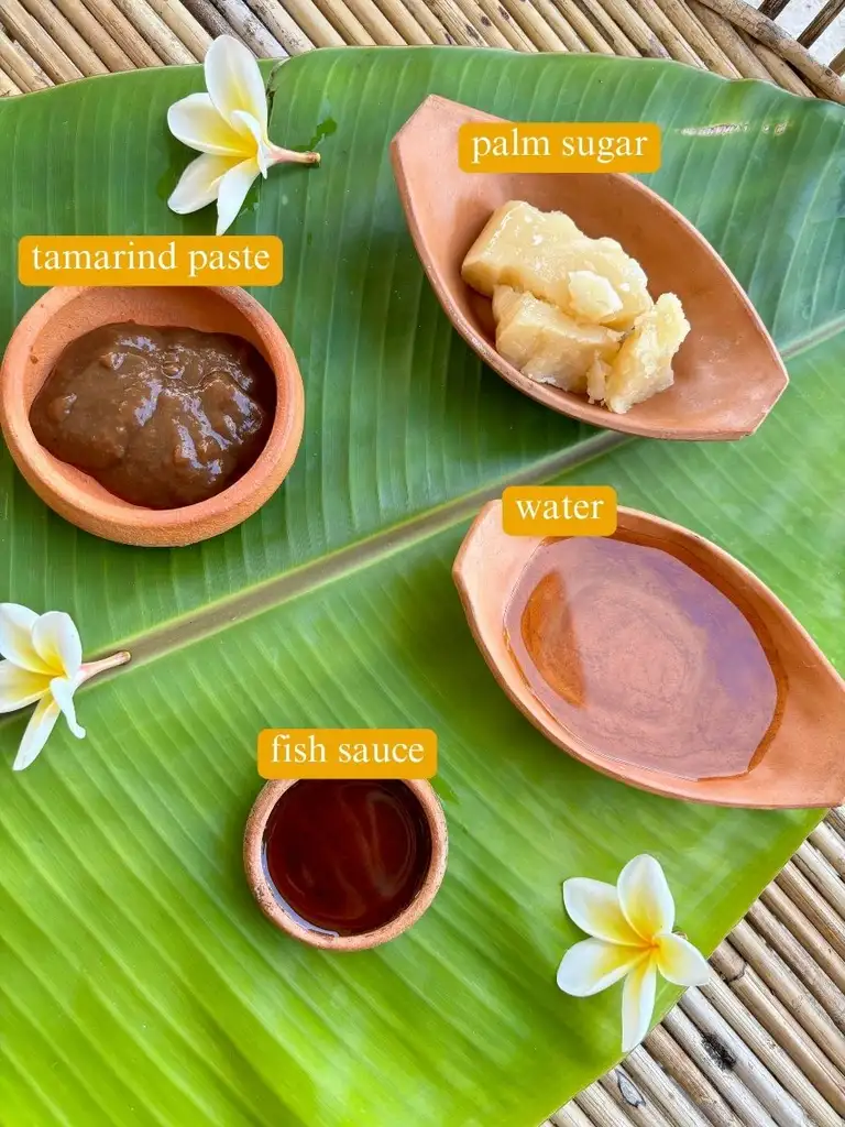 Top-view of ingredients for pad Thai sauce recipe: tamarind paste, fish sauce, water, and palm sugar.