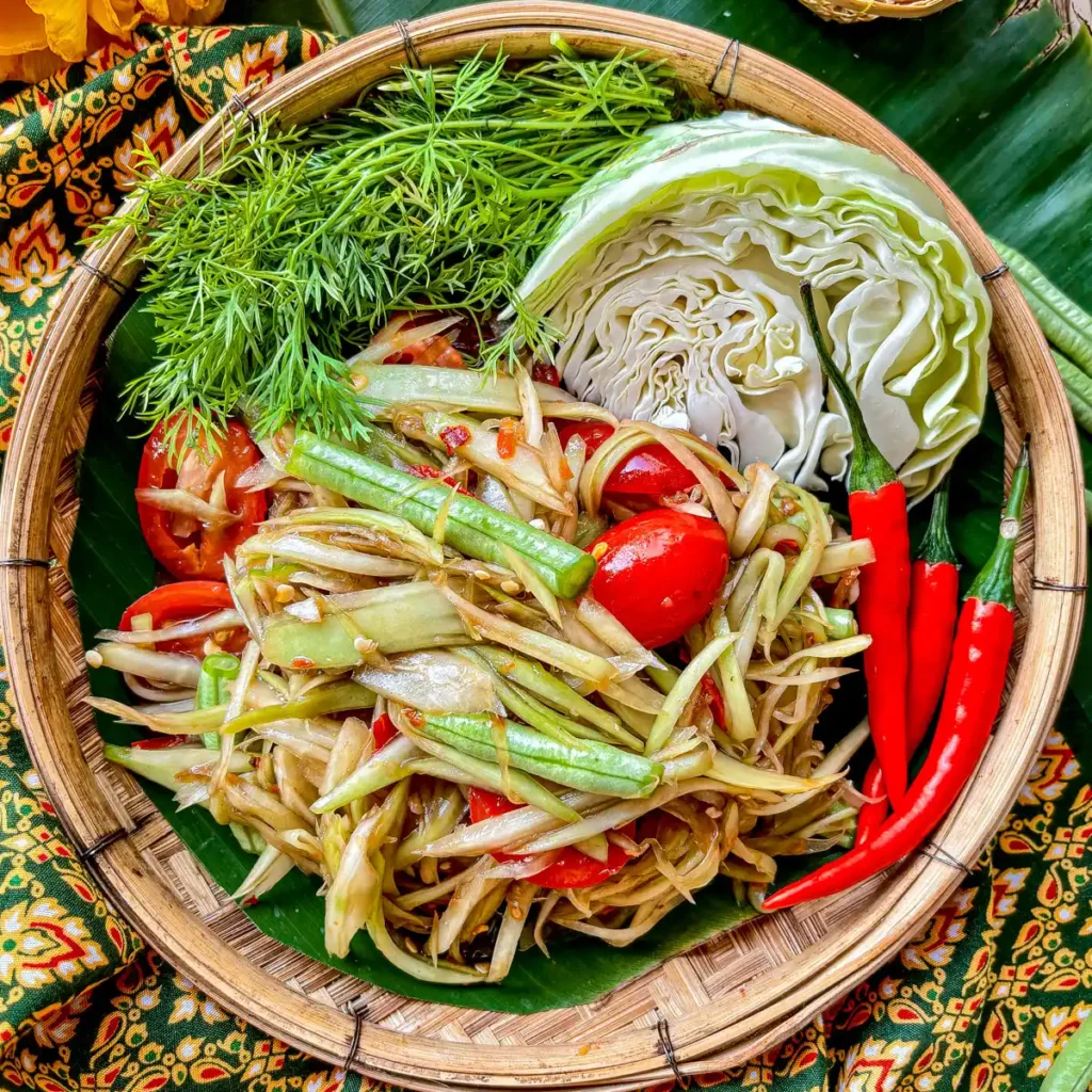 Close-up of Lao papaya salad served in a bamboo woven dish.