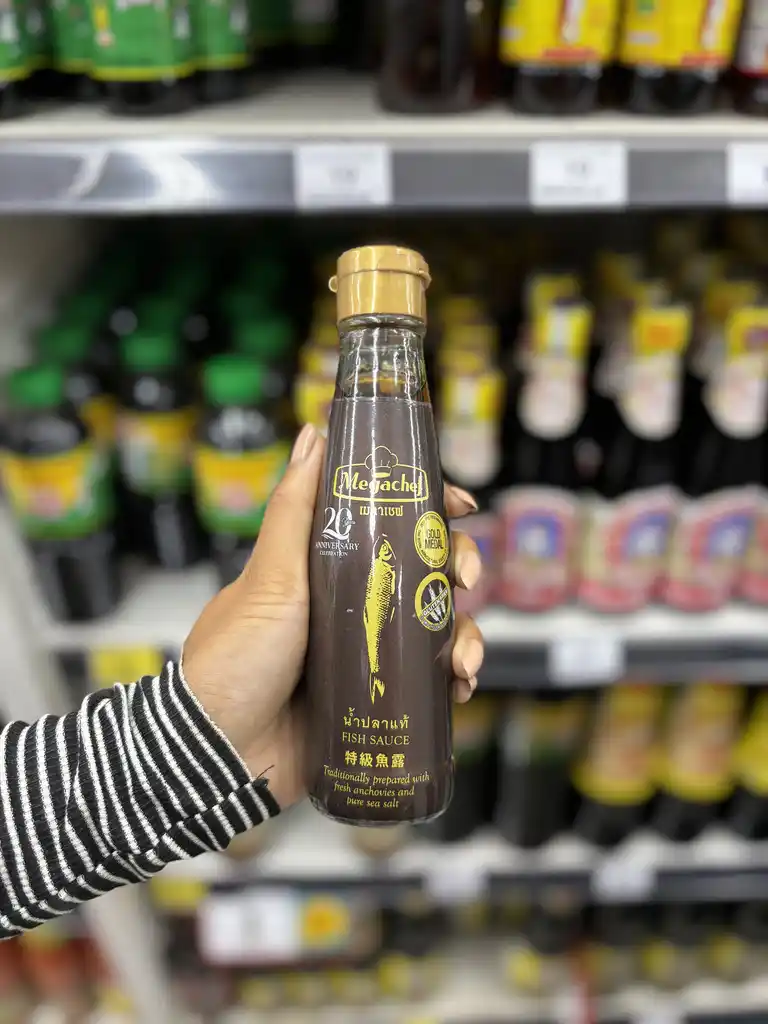 Bottle of megachef premium fish sauce being picked from a shelf.