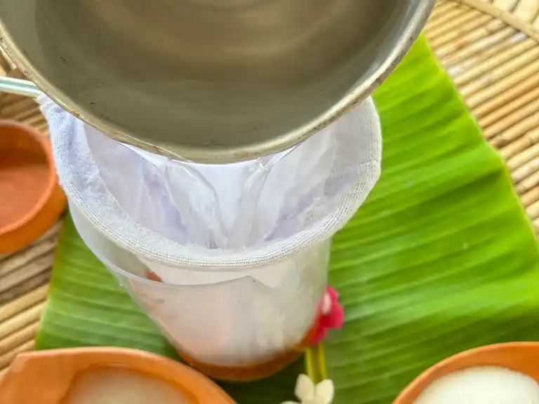 Pouring hot water for Thai tea through a cloth filter.