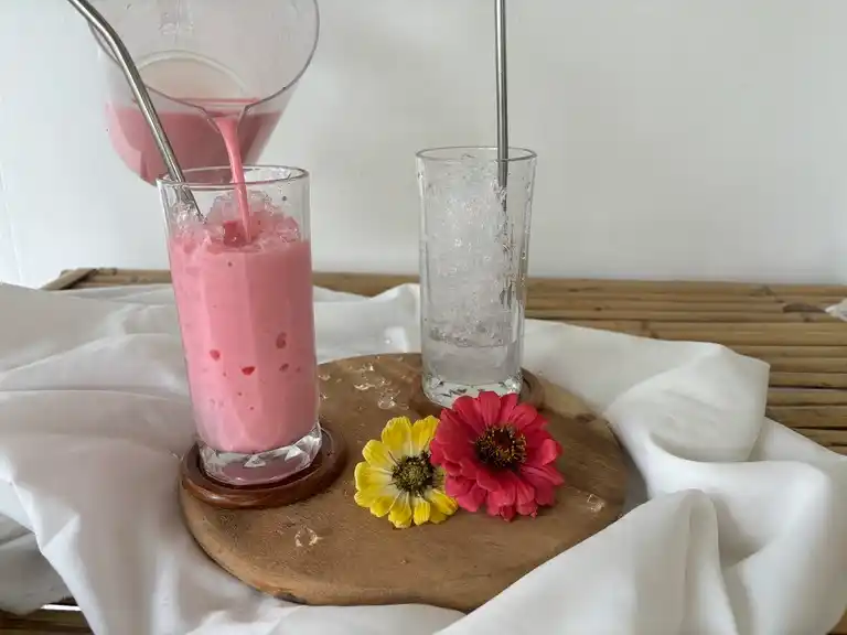 Pouring the sweet pink milk into a glass.