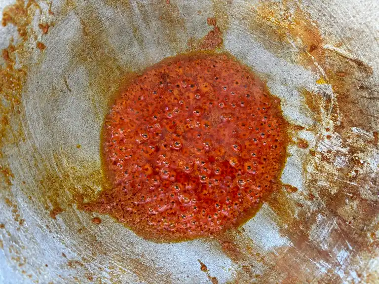 Red curry paste with coconut milk simmering in a wok.