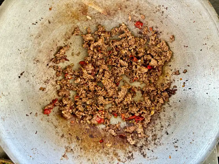Cooked ground meat in a wok after being tossed with stir-fry sauces and seasonings.
