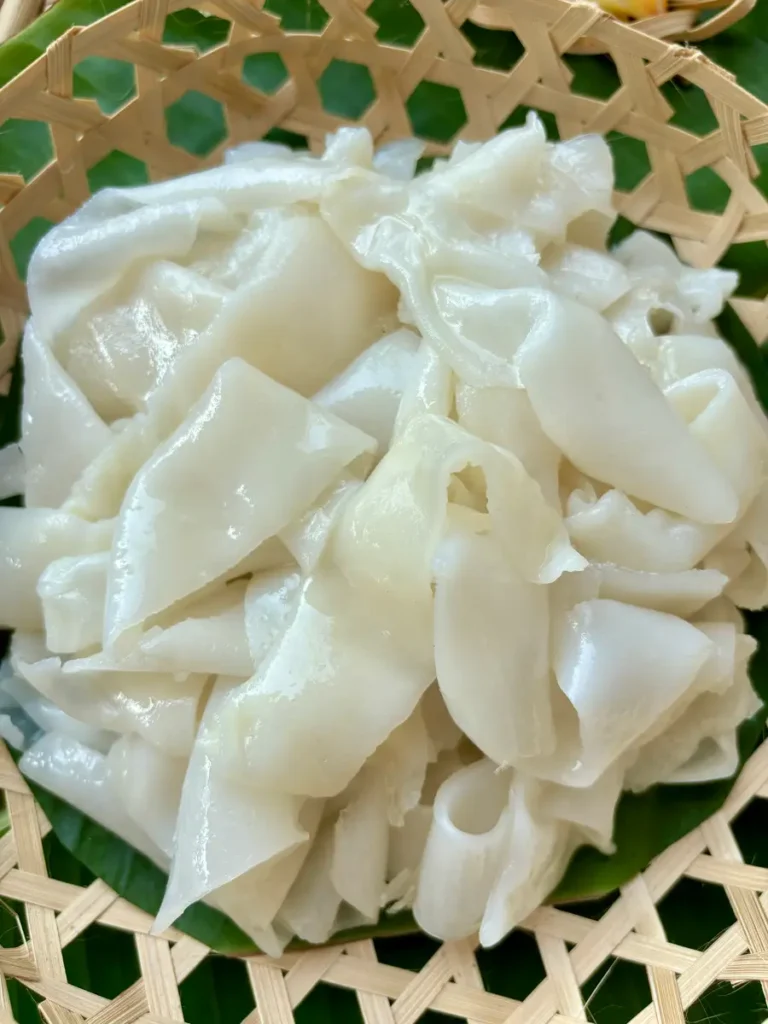 Close-up of homemade Thai sen yai noodles prepped for stir-frying.