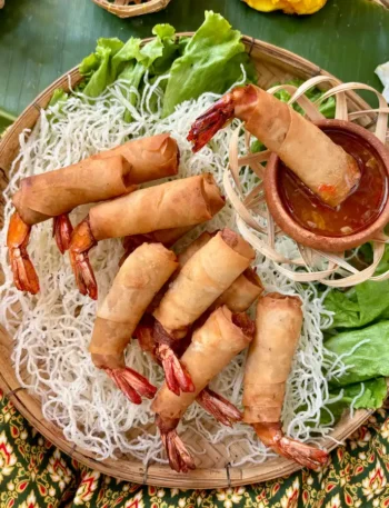 Thai shrimp in a blanket presented on a bamboo woven basket.