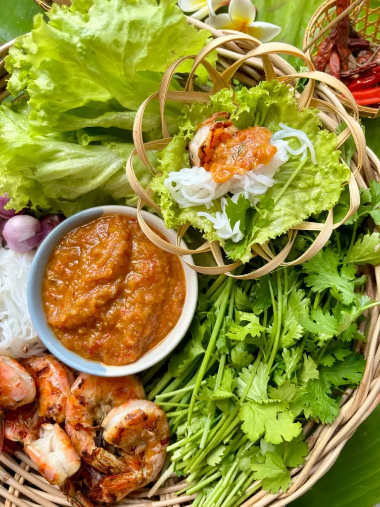 Shrimp lettuce wraps with peanut sauce, fresh vegetables, rice vermicelli, coriander, and chilies.