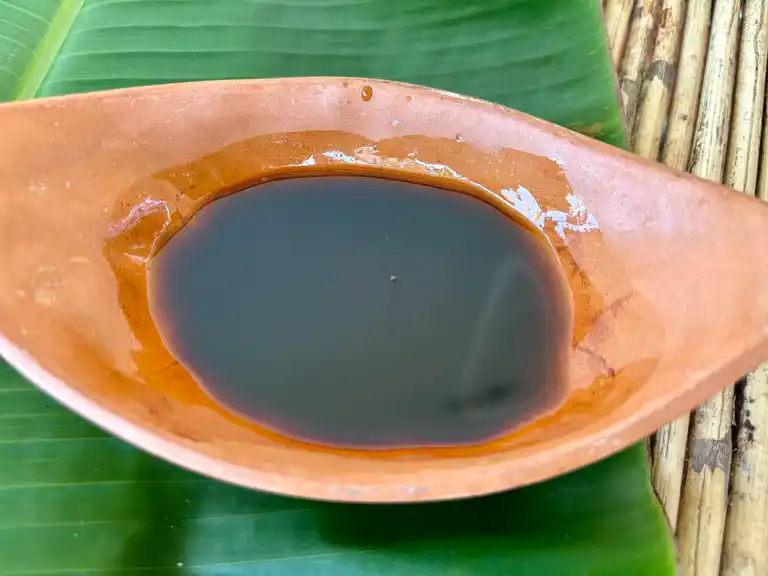 Sauce for stir-frying in a clay cup on banana leaf.