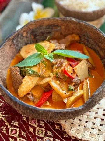 Thai bamboo shoot curry with beef and vegetables in a coconut shell.