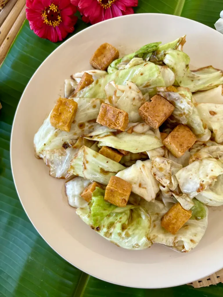 Thai fried cabbage with tofu, pad galam plee, served in a white dish.