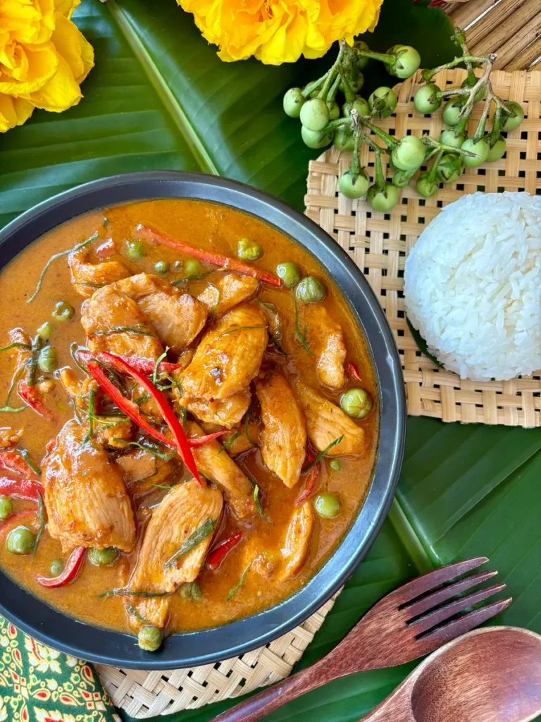 Authentic Thai panang chicken curry beside jasmine rice beside pea eggplants.