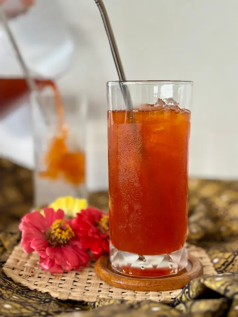 Thai lime iced tea, cha ma nao, served in a long glass with straw.