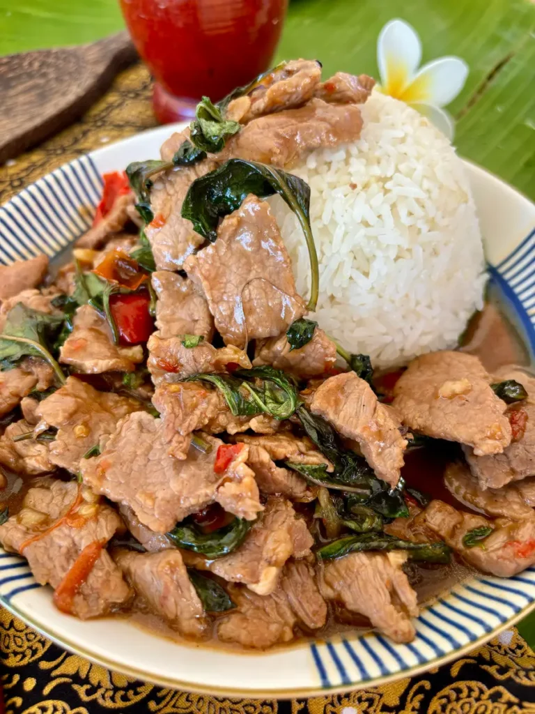 Close-up of pad horapa, Thai sweet basil stir-fry, showing beef and sweet basil mingled in a stir-fry sauce, on a bed of jasmine rice.