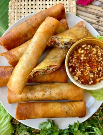 Thai vegetable spring rolls on a banana leaf with spicy dipping sauce.