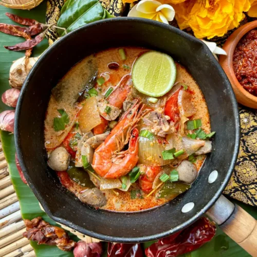 Tom yum talay, Thai seafood soup served in a pot, garnished with fresh herbs.