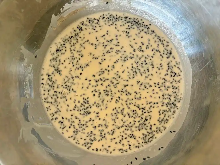 Batter mixed with black sesame seeds in bowl.