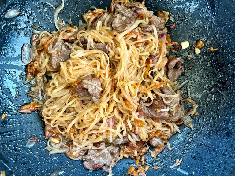 Beef noodles stir-fried in a wok.