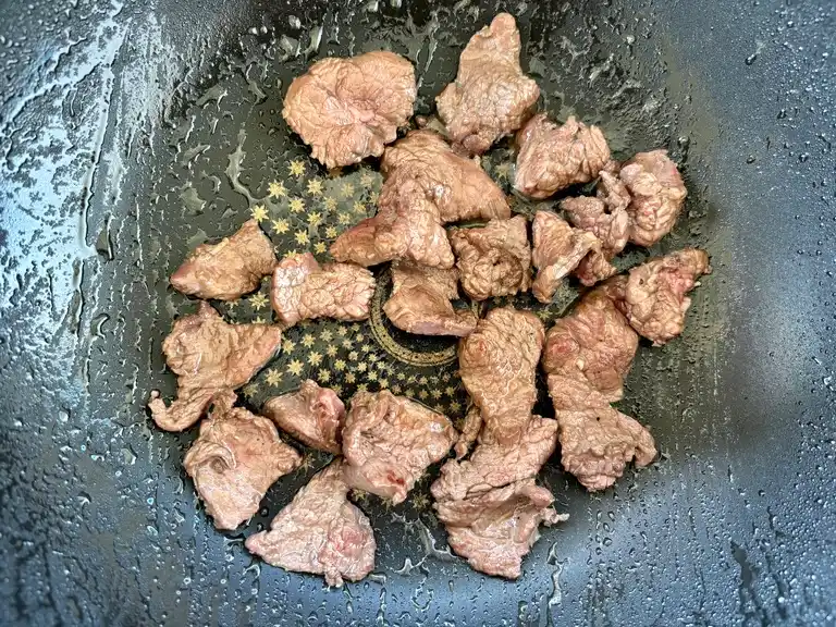 Beef pieces browning in wok.