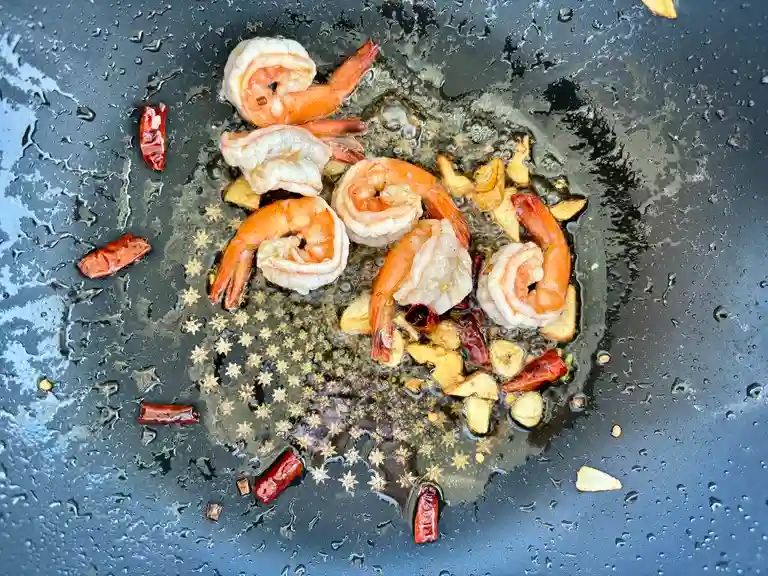 Cooked shrimp and spices in a wok.