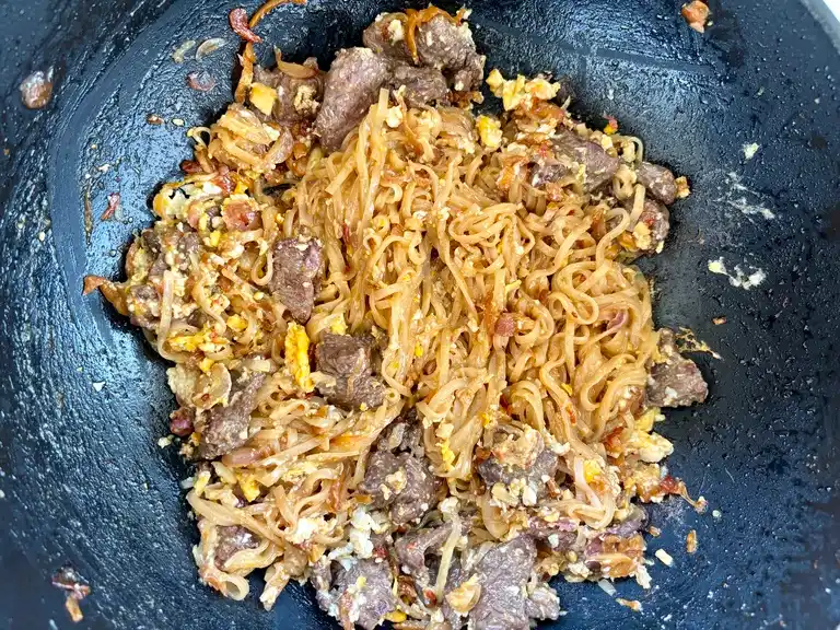 Fried noodles and beef in a wok.