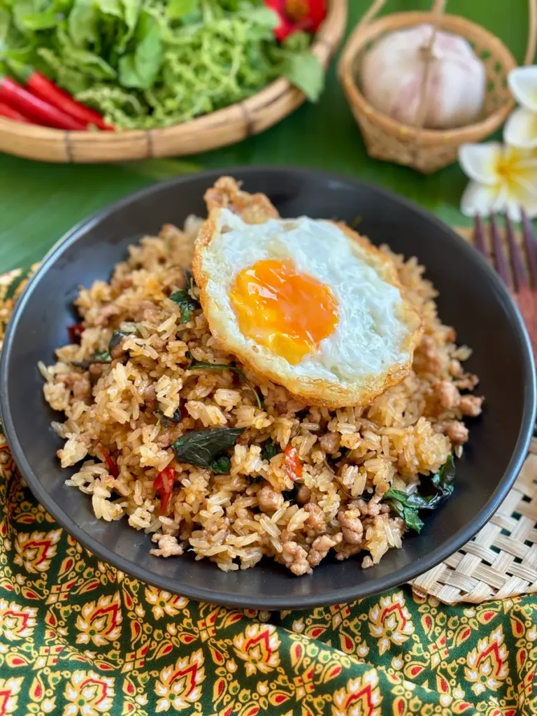 Fried rice holy basil in black dish topped with fried egg.